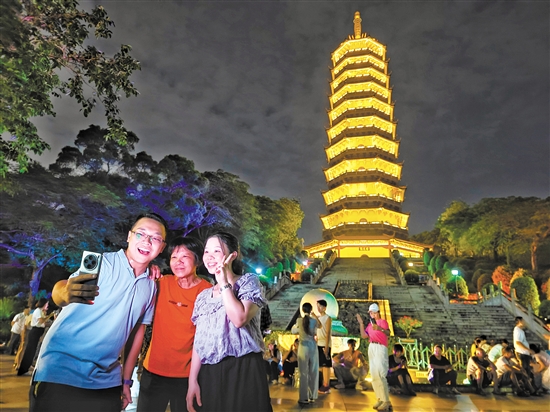 成功登頂?shù)氖忻衲贸鍪謾C與龍光塔合影。