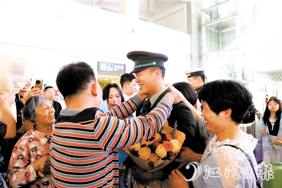 身著軍裝的返鄉(xiāng)退役士兵逐一出站，迎接他們的是鮮花與擁抱。