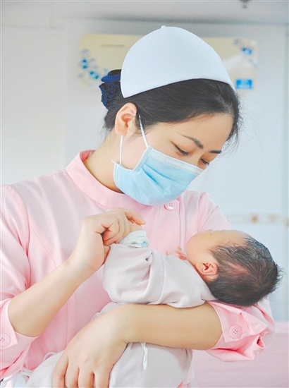 這是一雙托起生命的手。江門市中心醫(yī)院愛嬰?yún)^(qū)主管護師湯玲玲正在安撫哭鬧的寶寶。她一手環(huán)住襁褓，一手牽起寶寶的小手，動作舒緩而溫柔。在這里，生命的啼哭與溫柔的守護相遇，匯聚成世間至暖的力量。（林錦棠