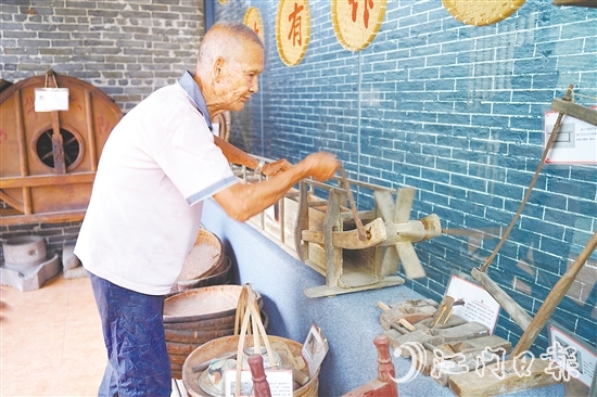 新華村打造農(nóng)耕文化展館，留住鄉(xiāng)村記憶。圖為村中老人向記者介紹農(nóng)具。