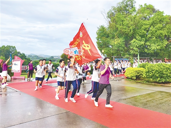 在臺山市武溪中學(xué)，老師揮舞著“中考加油”的紅旗為考生加油助威。