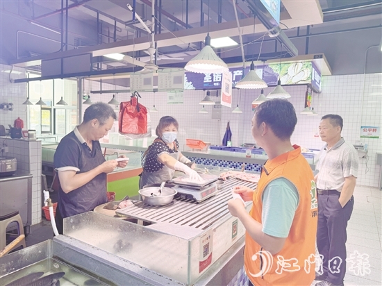 買(mǎi)菜易的平臺(tái)接單員李叔（橙色馬甲）正在魚(yú)攤旁等待取單。