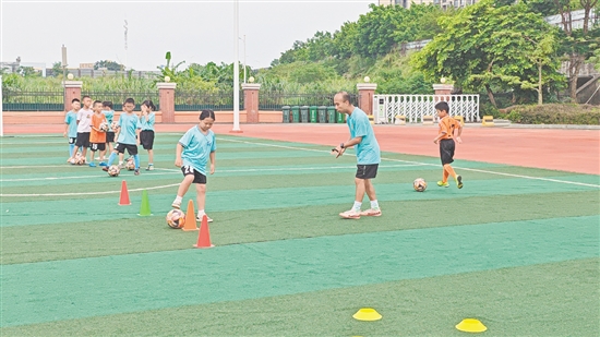 學(xué)生在教練的指導(dǎo)下學(xué)習(xí)足球技巧。