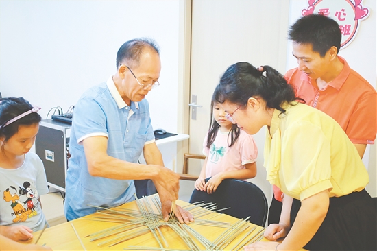 孩子和家長(zhǎng)在手藝人的指導(dǎo)下學(xué)習(xí)編織小竹筐。