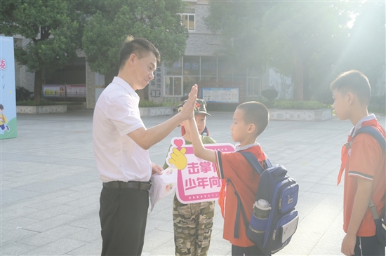 紫茶小學(xué)黨委書記譚國池與學(xué)生逐一擊掌。