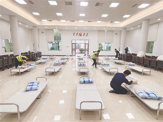 工作人員正在臨時庇護場所鋪設床位。