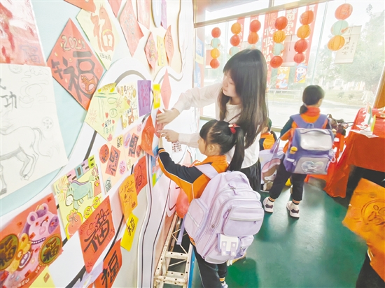 學生滿懷期許地把寄托新春祝福與新學期心愿的“?！弊肿髌窂堎N在學校精心準備的“馬到成功”墻前。