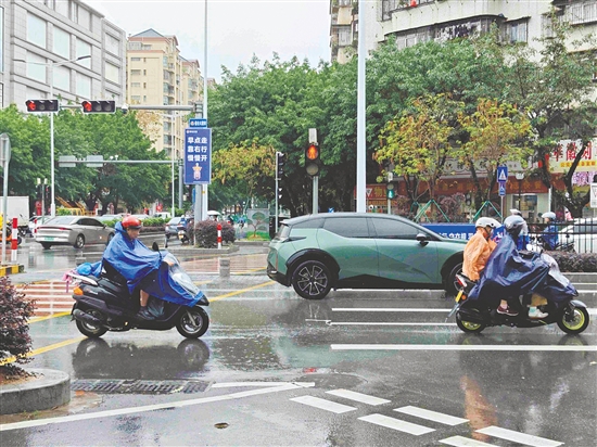 昨日，新會下起陣雨，市民紛紛穿上雨衣。