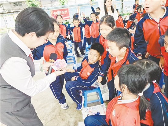 宣講員以第五套人民幣為教具，讓孩子們學(xué)會識假技巧。