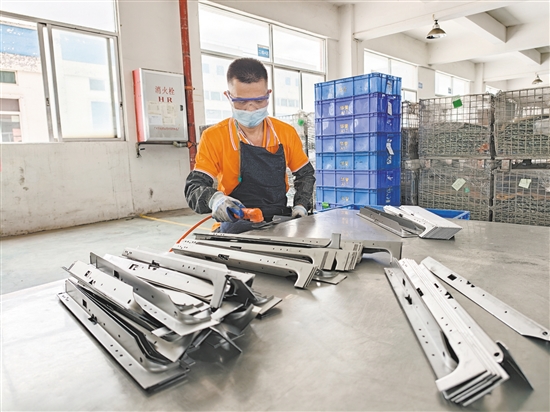 在江門市華譽制造有限公司的生產(chǎn)車間，52歲的殘疾人員工黃日道在認真打磨零部件。