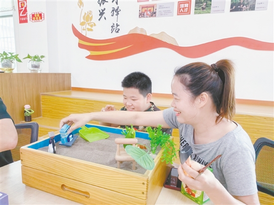 家長(zhǎng)和孩子分別認(rèn)真挑選沙具，專(zhuān)注地搭建場(chǎng)景、勾勒畫(huà)面。