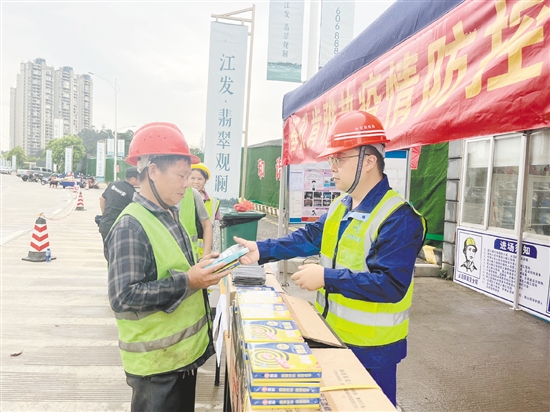 工地施工人員排隊領(lǐng)取防蚊用品。