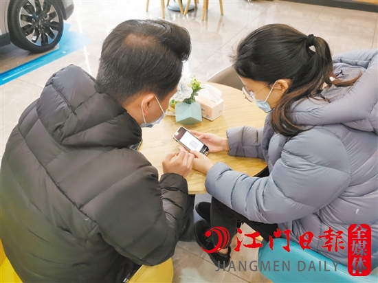 新能源汽車銷售人員協(xié)助車主用手機(jī)進(jìn)行投保新能源汽車險(xiǎn)。